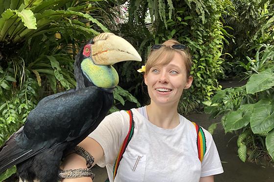 Photo of a Chatham University student in a jungle with a large exotic bird perched on her arm
