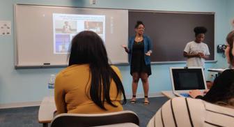 图为一名妇女站在教室前用投影仪讲课.