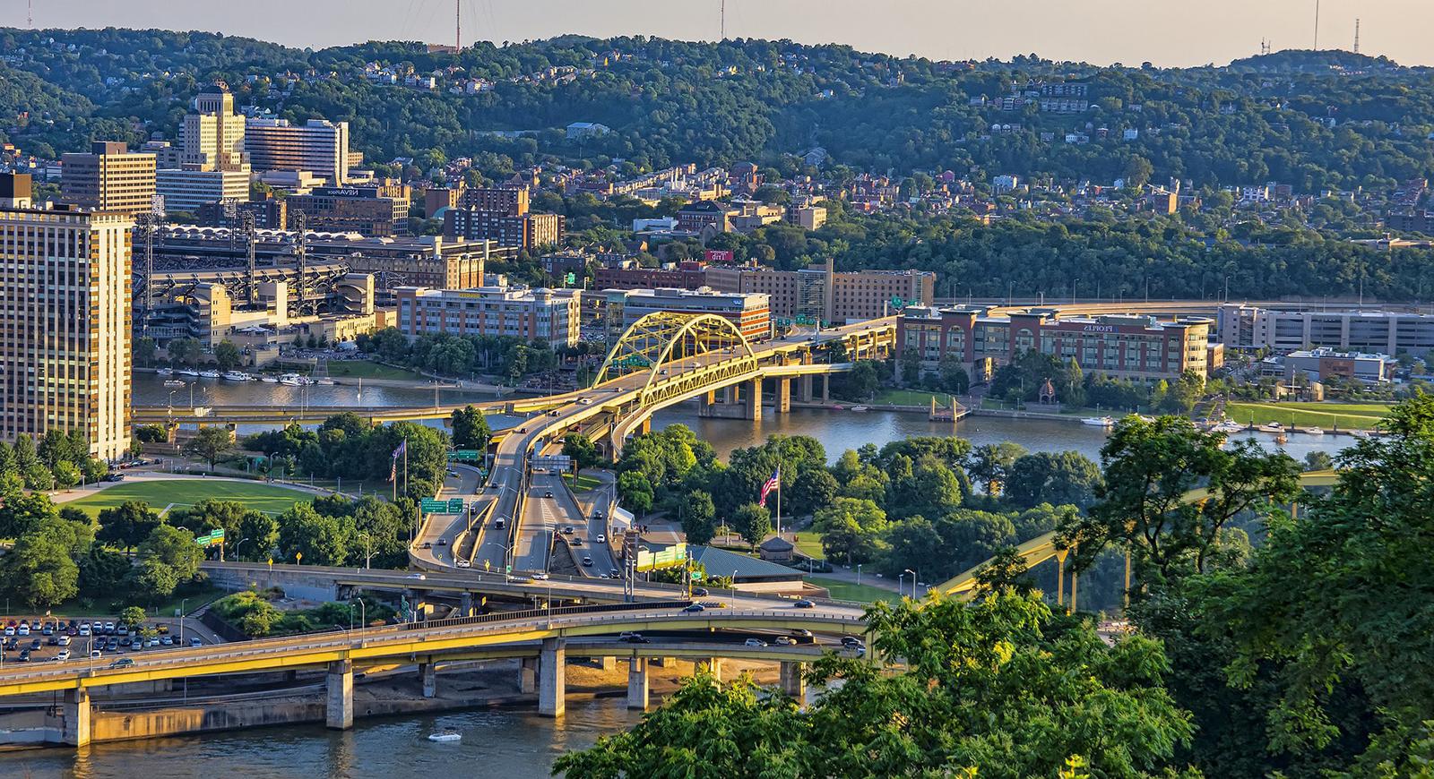 夕阳下，匹兹堡的黄色桥梁和起伏的山丘衬托着河流. 