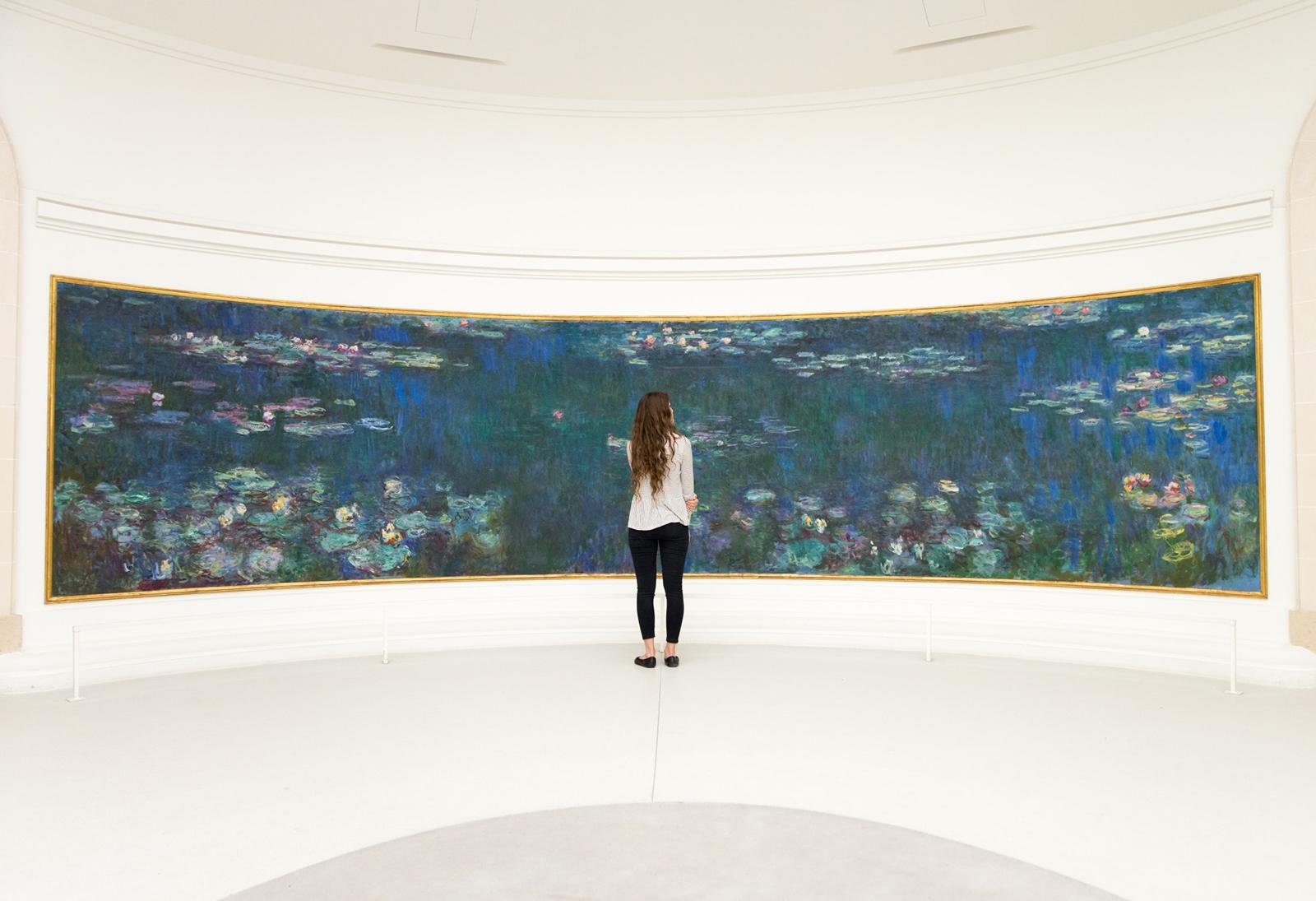 Photo of a woman standing in front of Monet's Water Lillies. 