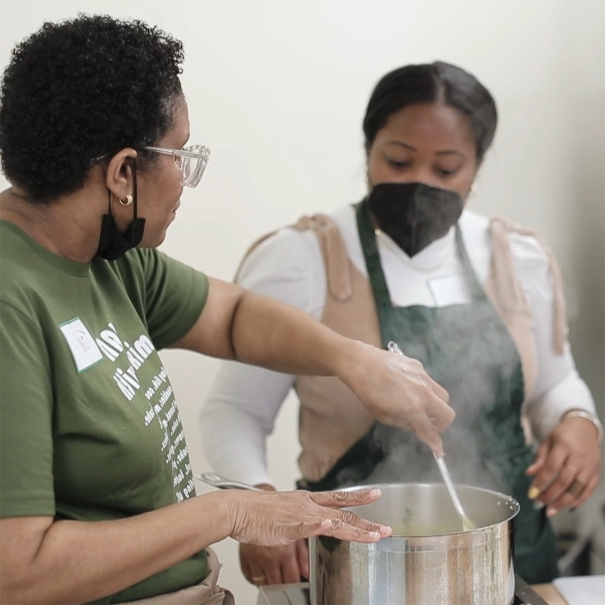 Photo of Toni Simpson stirring food in a pot, while she instructs a cooking class