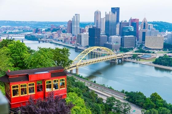 Photo of the Pittsburgh skyline featuring Mount Washington and a red incline car. 
