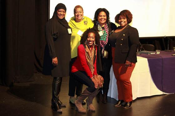 Photo of a group of female panel members, posing on stage after a talk