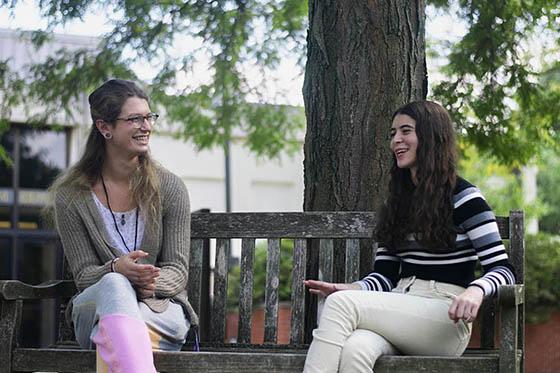 Photo of a student and a success coach speaking and laughing together on a bench