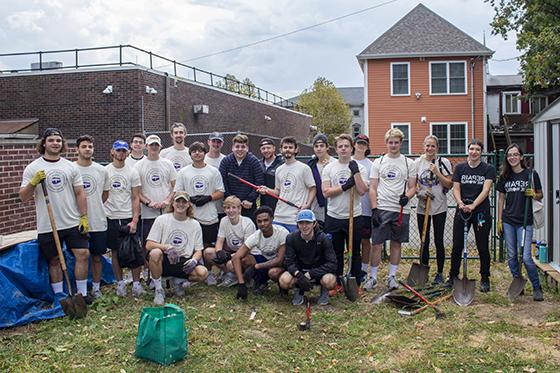 Photo of a group of Chatham University students pose together after doing yard work together during a volunteer day